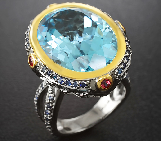 Серебряное кольцо с голубым топазом, рубинами и синими сапфирами